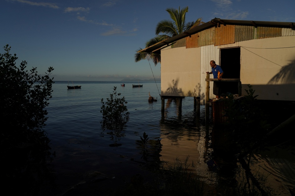 Local resident of Veivatuloa Village in Fiji looks out at seawater flooding around his home at high tide in July 16, 2022.