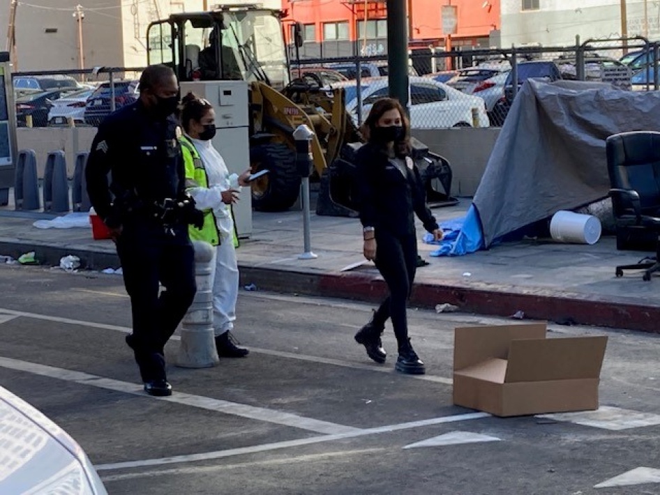 LASAN worker, an LAPD officer and a representative of Council District 14 participating in the sweep, as a loader sits ready to destroy a tent