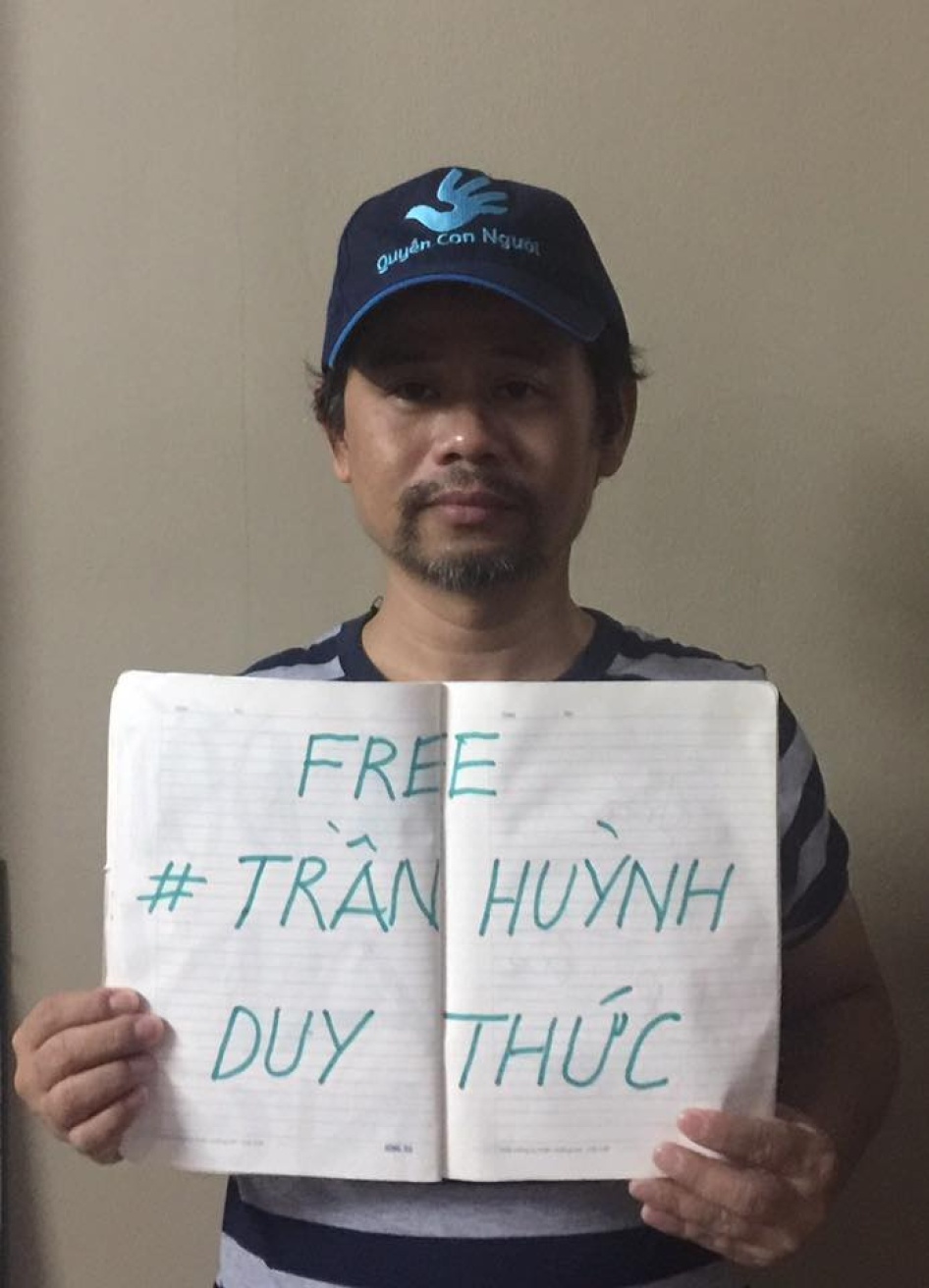 Phan Van Bach carries a sign supporting political prisoner Tran Huynh Duy Thuc.