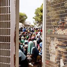 People wait in a migrant holding area