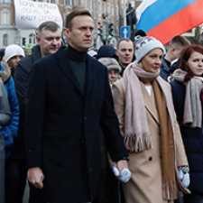 Alexei Navalny walks among large crowd. 