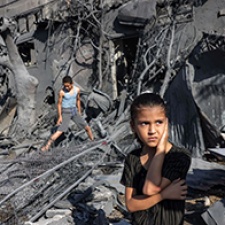 Children stand in rubble. 