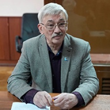 Oleg Orlov sits at desk. 