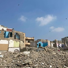 Houses stand in front of rubble in Pakistan. 