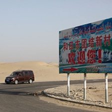 A car and billboard stand beside road. 