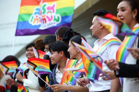 People wave rainbow flags in Thailand. 