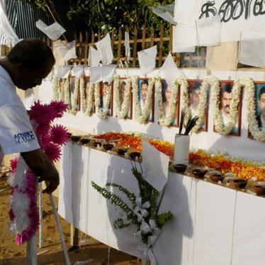 A member of the French aid group Action Contre La Faim places a wreath in front of the photographs of his 17 slain colleagues at their memorial in Batticaloa, Sri Lanka on August 11, 2006.