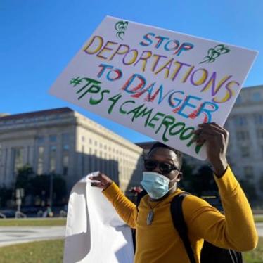 A person holding a protest sign that reads "Stop Deportations to Danger"