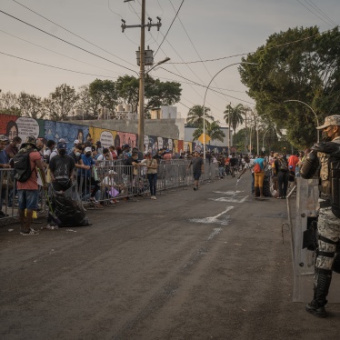 A member of the national guard keeps order as migrants wait outside the Mexican Commission for Refugee Assistance to get their applications processed in Tapachula, Chiapas state, Mexico, April. 12, 2022. 