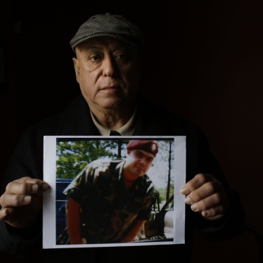 A man holds a photo of his son wearing a military uniform