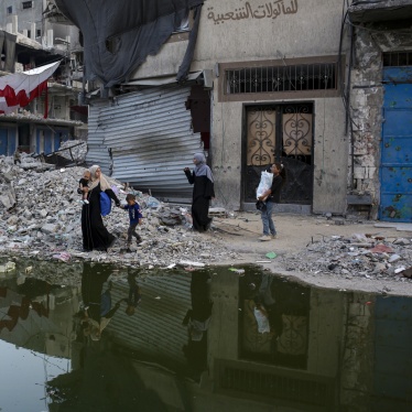 Palestinians displaced by the Israeli air and ground offensive walk next to sewage flowing into the streets of the southern town of Khan Younis in Gaza, July 4, 2024.