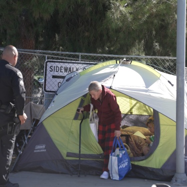 Police remove an unhoused woman from her tent