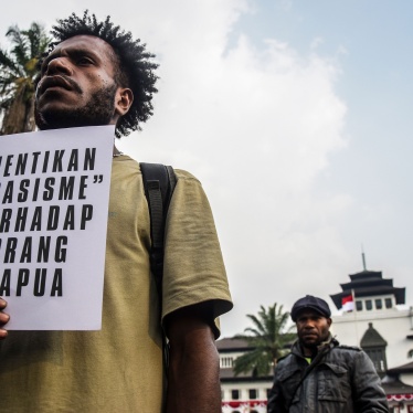 A man holds a sign in Indonesian at a protest