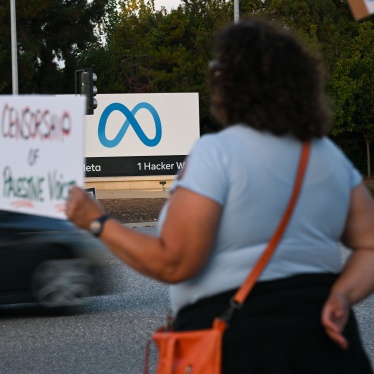 A person holding a protest sign outside of the Meta headquarters