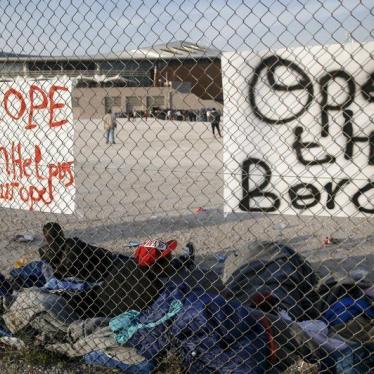Migrants, who were stranded between Greece and Macedonia, rest next to placards hung on a metal fence, outside the Tae Kwon Do stadium at the southern suburb of Faliro, in Athens, Greece, December 14, 2015. 