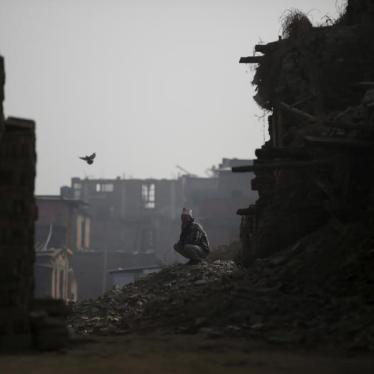 A man sits on top of the debris of houses damaged during the earthquake last year in Bhaktapur, Nepal, January 29, 2016.