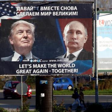 Pedestrians cross the street behind a billboard showing a pictures of Donald Trump and Vladimir Putin in Danilovgrad,  Montenegro.