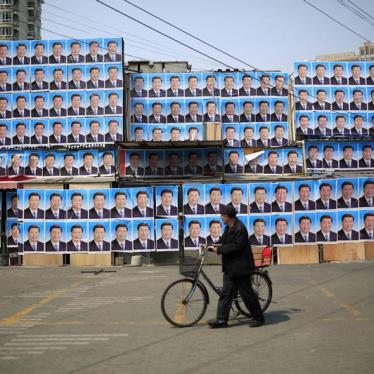 A man with a bicycle walks past a building covered in posters of Chinese President Xi Jinping in Shanghai, China, on March 26, 2016.