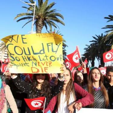Tunisian students hold flags and placards during a march in memory of 12 presidential guards who were killed in an attack in Tunis.
