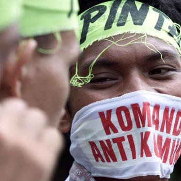 An Indonesian youth covers his face with a mask reading "Anti Communist Command" during a protest in front of the presidential palace in Jakarta May 20, 2000.