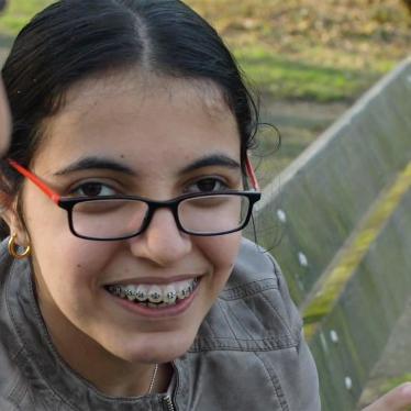 close up of Nujeen Mustafa, a young Syrian disability rights advocate, sitting on a park bench smiling