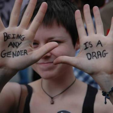 A woman taking part in London Pride, 2012, holds up her hands to show the words "being any gender is a drag".