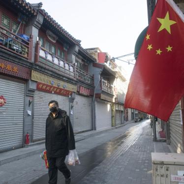 A man wearing a mask walks past closed stores in Beijing on March 13, 2020, amid the spread of the new coronavirus.